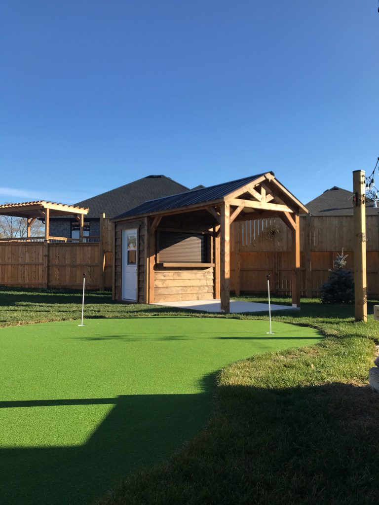 Backyard bar with covered porch next to a putting green